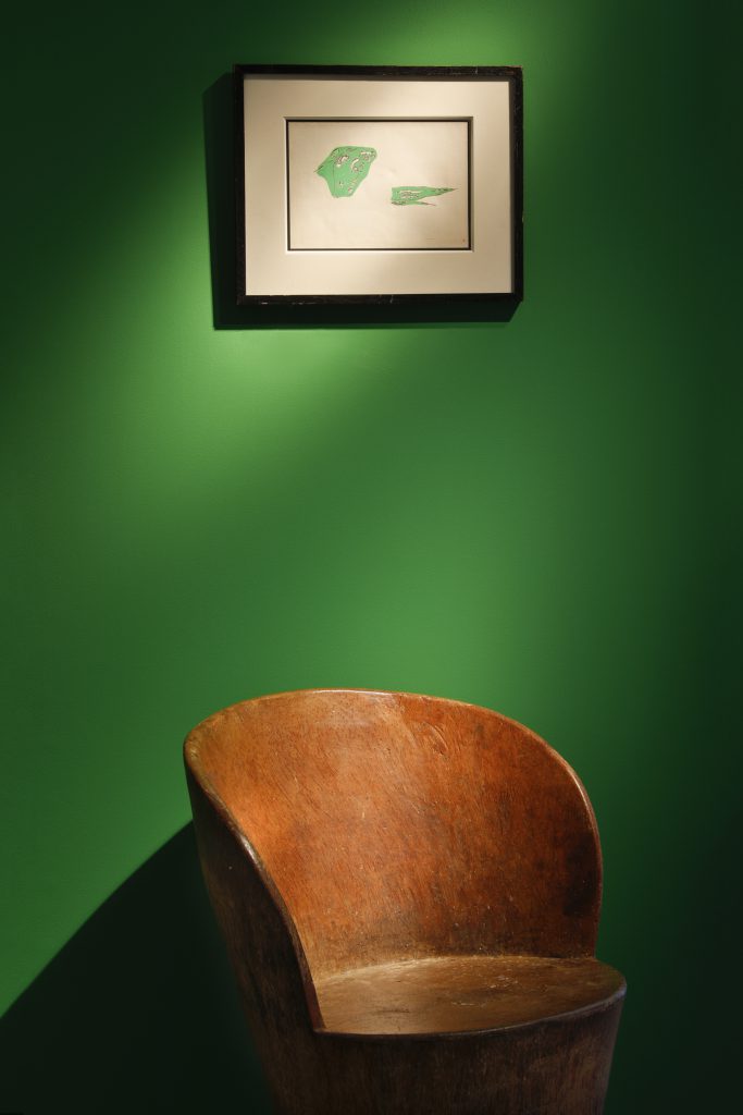 Green wall with a white picture on it and a wooden chair