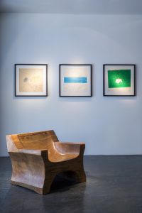 white wall with 3 pictures on it and a wooden chair